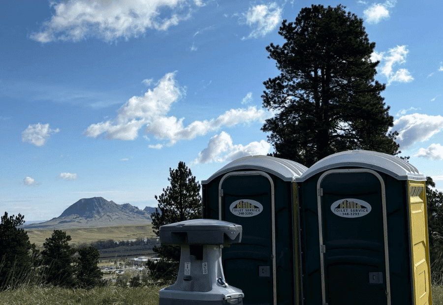 Two Hills Septic Toilet Service Portable Toilets with hand washing station in front near Sturgis, SD with Bear Butte in the background